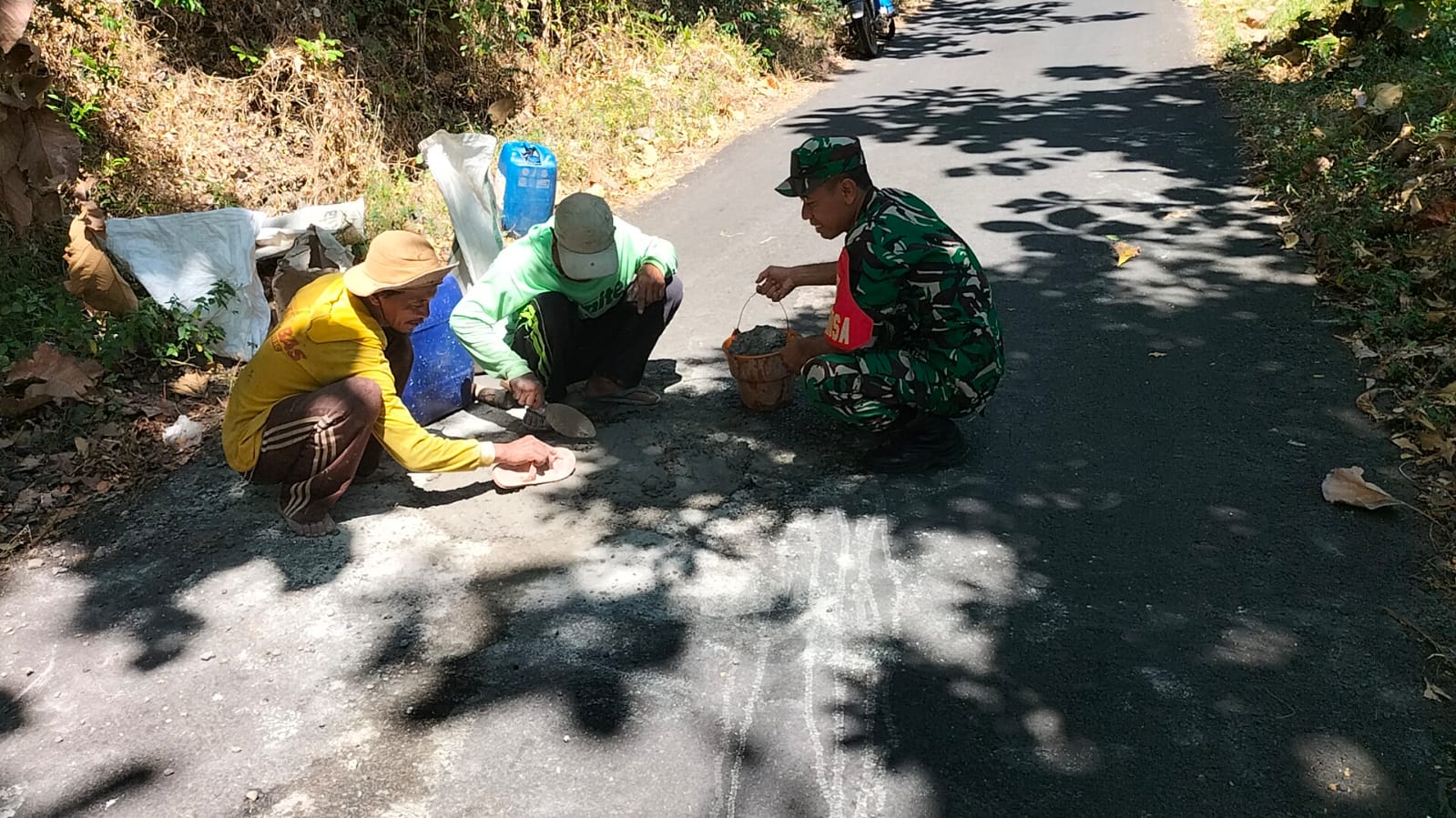 Wujud Kemanunggalan TNI-Rakyat, Babinsa Jatibanteng Dampingi Warga Perbaiki Jalan Desa